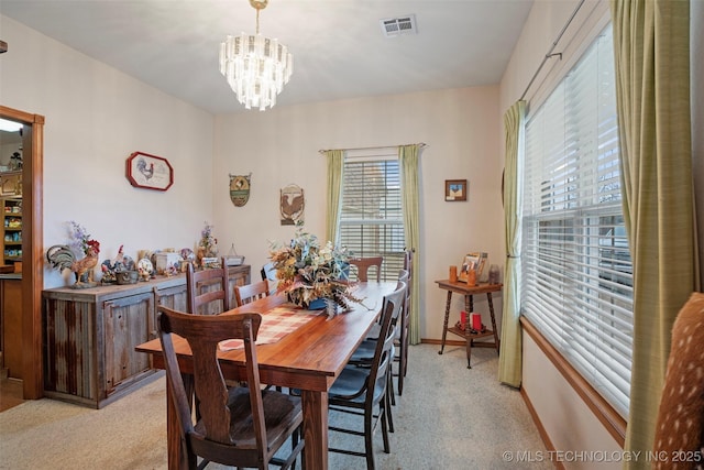 dining space with light carpet and a chandelier