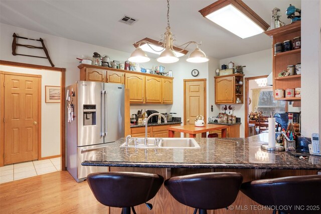 kitchen featuring high quality fridge, kitchen peninsula, sink, and a breakfast bar area