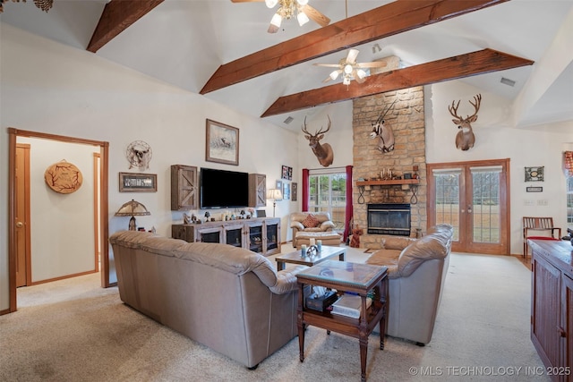 carpeted living room featuring a stone fireplace, high vaulted ceiling, ceiling fan, beam ceiling, and french doors