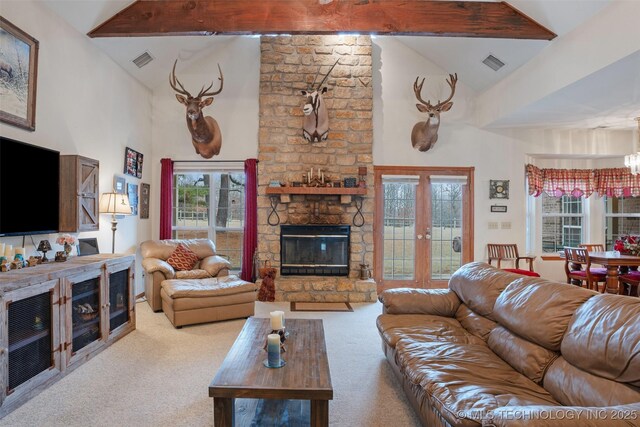 living room featuring beamed ceiling, carpet flooring, and a stone fireplace