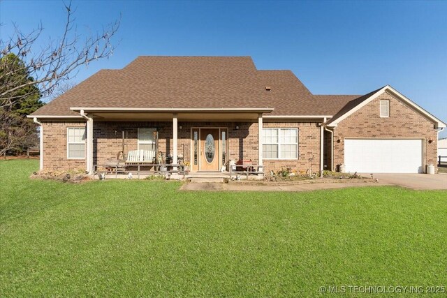 rear view of property with a garage, covered porch, and a lawn