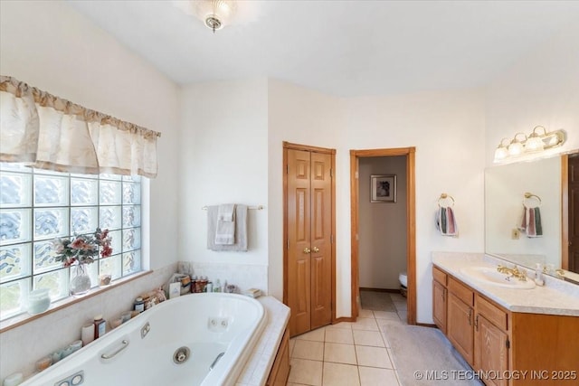 bathroom featuring vanity, a relaxing tiled tub, tile patterned floors, and toilet