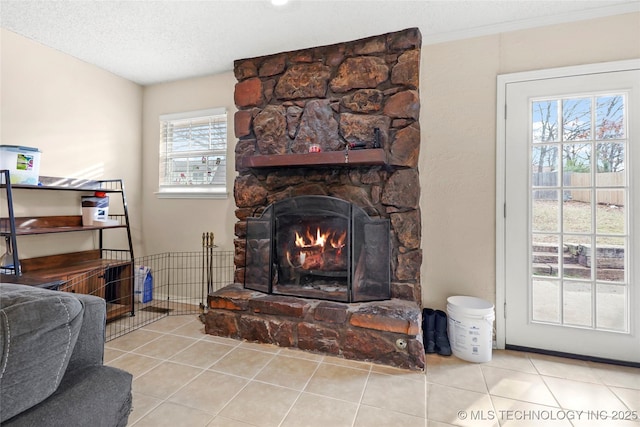 tiled living room featuring a textured ceiling, plenty of natural light, and a stone fireplace