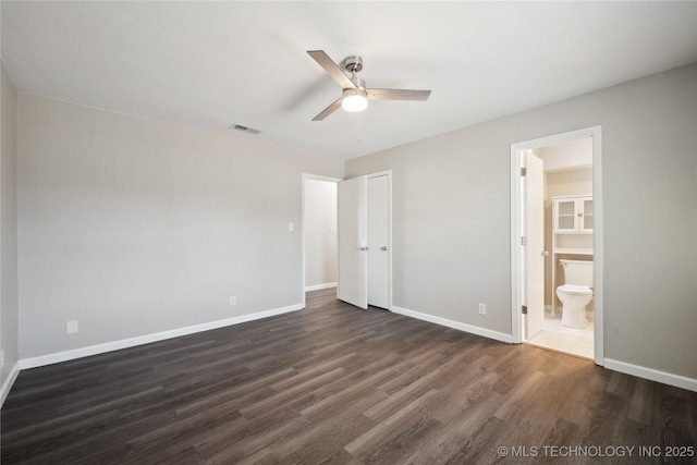 unfurnished bedroom with ceiling fan, dark wood-type flooring, and ensuite bath