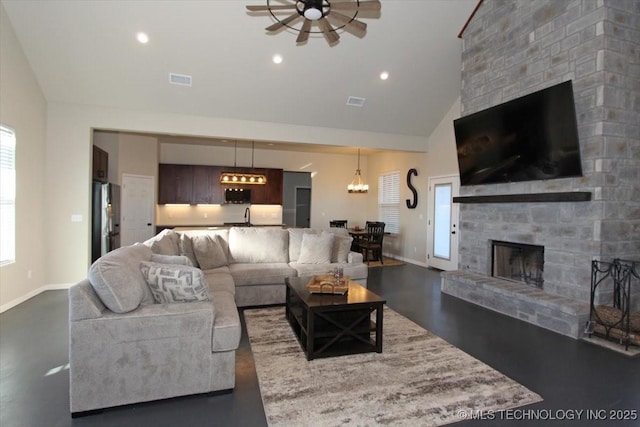 living room featuring a fireplace, ceiling fan with notable chandelier, high vaulted ceiling, and plenty of natural light