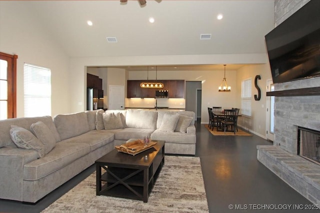 living room with a fireplace, a chandelier, and a high ceiling