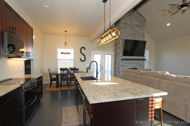 kitchen featuring pendant lighting, a kitchen island with sink, sink, light stone countertops, and black / electric stove