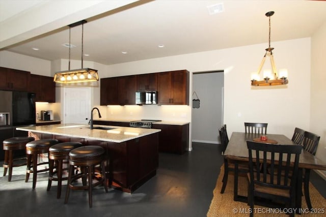 kitchen featuring pendant lighting, a kitchen island with sink, sink, stainless steel electric range oven, and dark brown cabinets