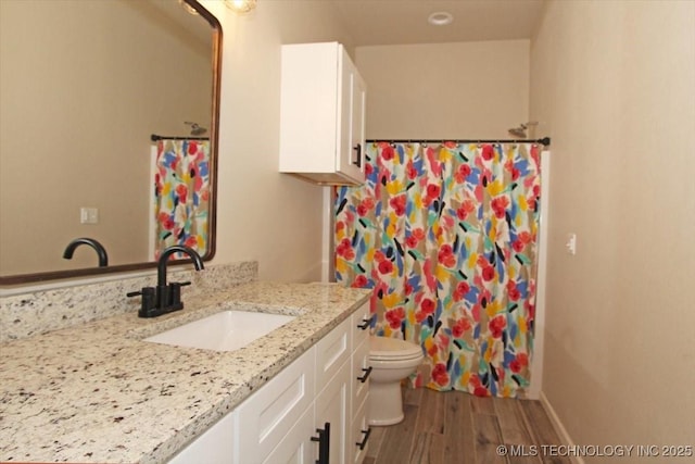 bathroom featuring toilet, vanity, and hardwood / wood-style flooring