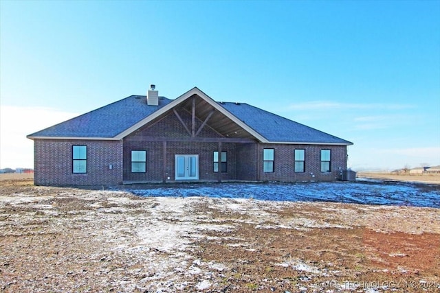 snow covered house with central AC unit and french doors