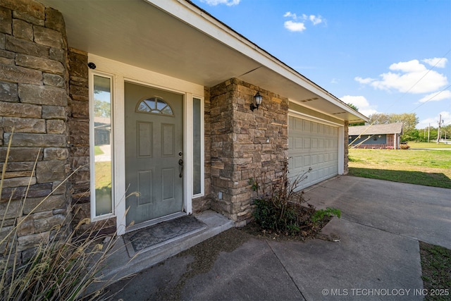 view of exterior entry with a yard and a garage