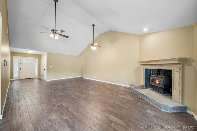 unfurnished living room featuring a wood stove, ceiling fan, wood-type flooring, and vaulted ceiling