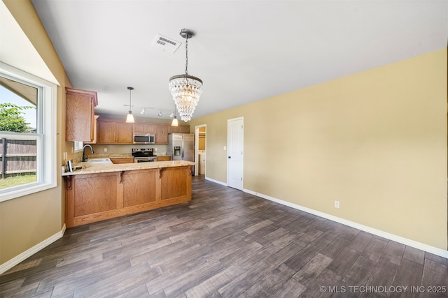 kitchen featuring sink, decorative light fixtures, appliances with stainless steel finishes, a notable chandelier, and kitchen peninsula