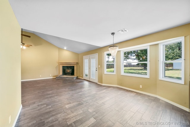 unfurnished living room with hardwood / wood-style floors, ceiling fan with notable chandelier, and lofted ceiling