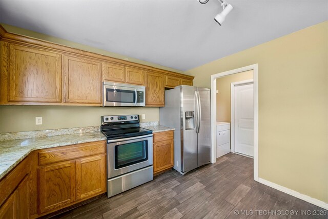 kitchen with light stone countertops, rail lighting, stainless steel appliances, dark hardwood / wood-style flooring, and washer / clothes dryer