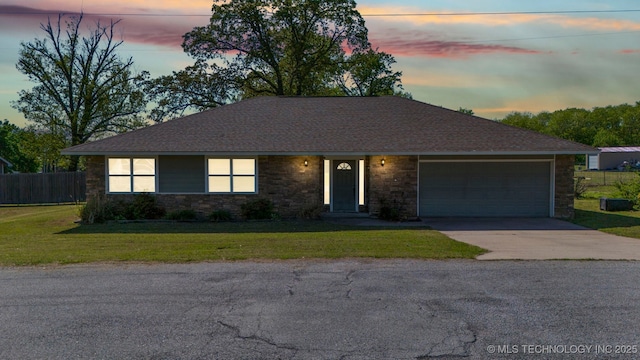 single story home featuring a lawn and a garage