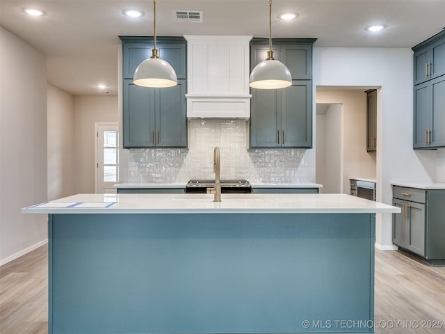 kitchen with tasteful backsplash, hanging light fixtures, and light hardwood / wood-style flooring