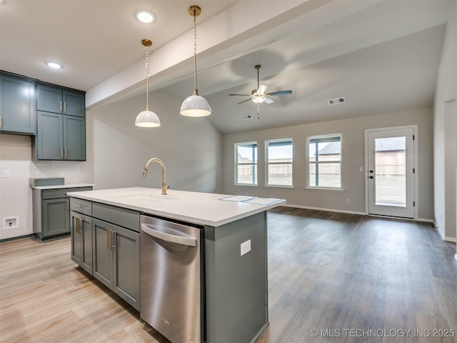 kitchen featuring vaulted ceiling, decorative light fixtures, sink, a center island with sink, and light wood-type flooring