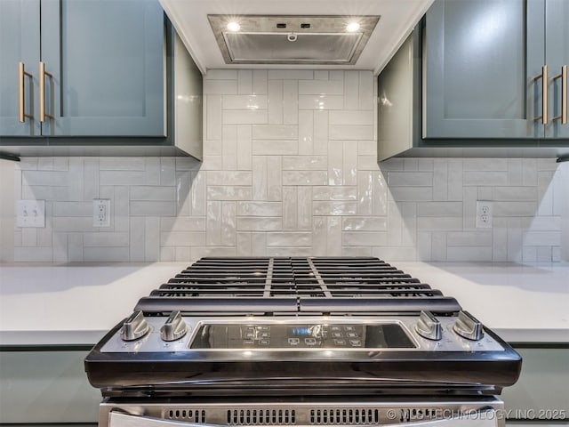 kitchen with blue cabinets, exhaust hood, backsplash, and stainless steel gas stove