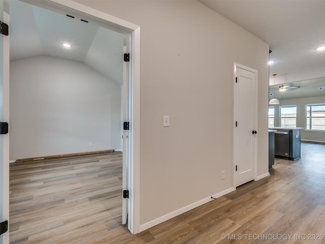 hallway with lofted ceiling and light wood-type flooring