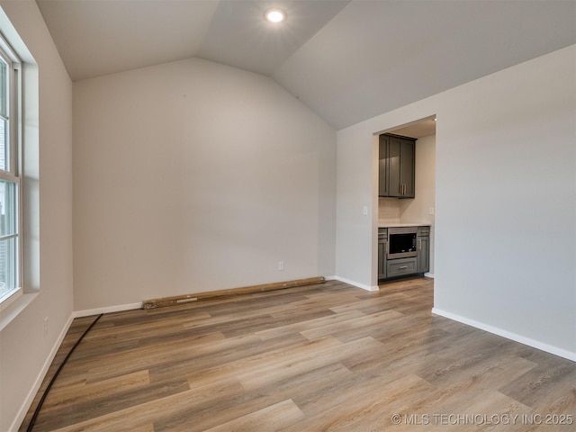 unfurnished living room featuring vaulted ceiling and light wood-type flooring