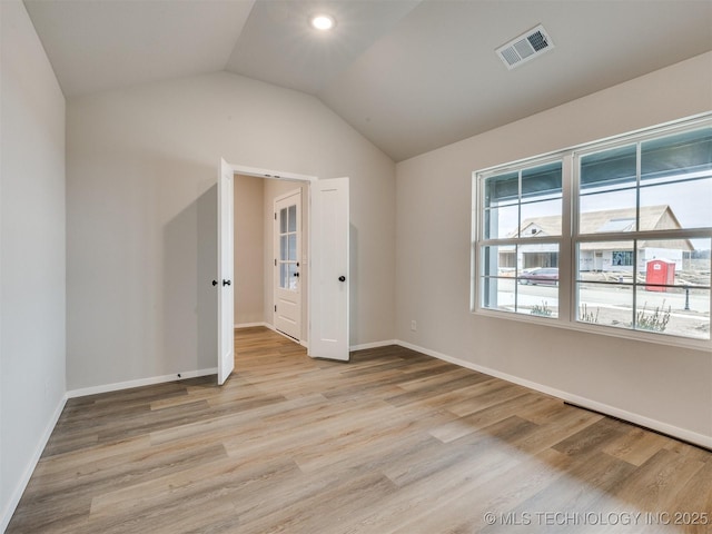 spare room featuring lofted ceiling and light wood-type flooring