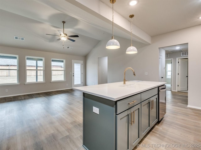 kitchen featuring pendant lighting, sink, an island with sink, stainless steel dishwasher, and light wood-type flooring