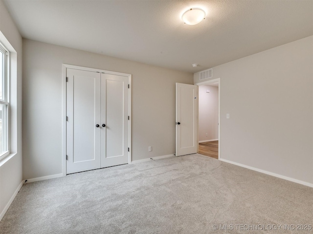 unfurnished bedroom with light carpet and a closet