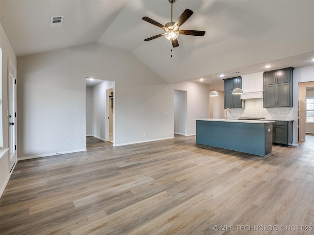 kitchen featuring light hardwood / wood-style flooring, sink, a center island with sink, and decorative light fixtures