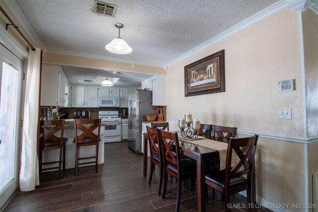 dining room featuring dark wood-type flooring, a textured ceiling, and ornamental molding