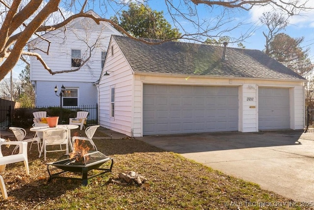 view of side of home with a garage and an outdoor fire pit