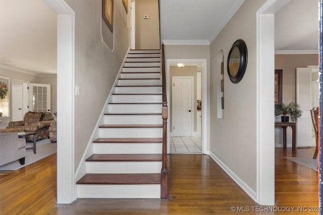 stairway with wood-type flooring and ornamental molding