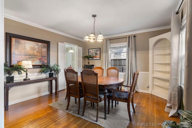 dining area with a notable chandelier, built in features, crown molding, and dark wood-type flooring