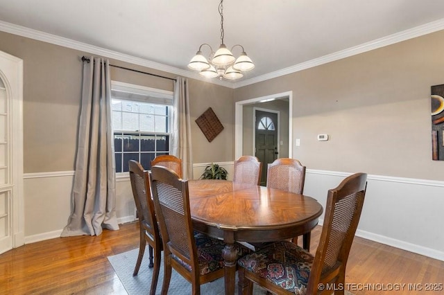 dining area featuring hardwood / wood-style flooring, ornamental molding, and an inviting chandelier