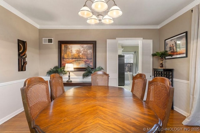 dining space featuring hardwood / wood-style flooring, crown molding, and an inviting chandelier