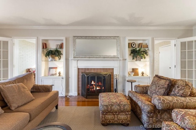 living room with wood-type flooring, ornamental molding, and a fireplace