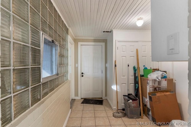 doorway to outside with light tile patterned floors and ornamental molding