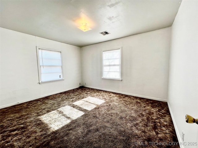 spare room with dark colored carpet and a healthy amount of sunlight