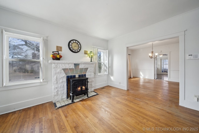 living room with hardwood / wood-style floors, an inviting chandelier, a wood stove, and plenty of natural light