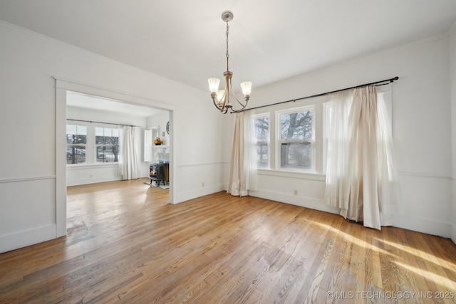 unfurnished dining area with a chandelier, hardwood / wood-style floors, and a wood stove