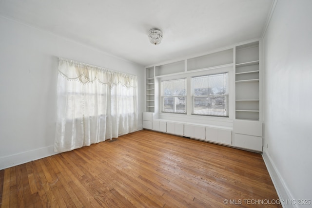 unfurnished room with built in features and wood-type flooring