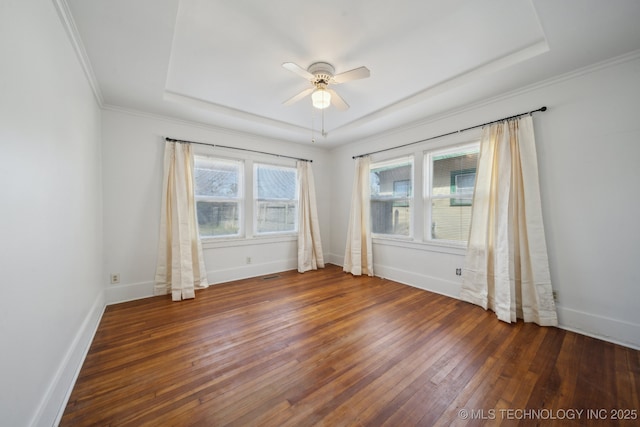 empty room featuring ornamental molding, a tray ceiling, ceiling fan, and dark wood-type flooring