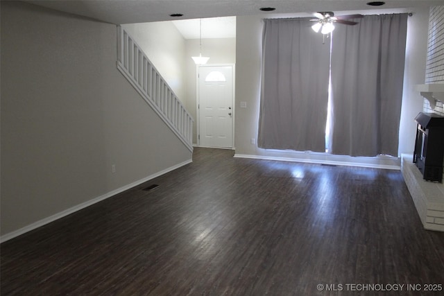 unfurnished living room featuring ceiling fan, a fireplace, and dark hardwood / wood-style flooring