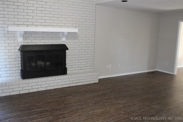 unfurnished living room with a brick fireplace and dark hardwood / wood-style floors