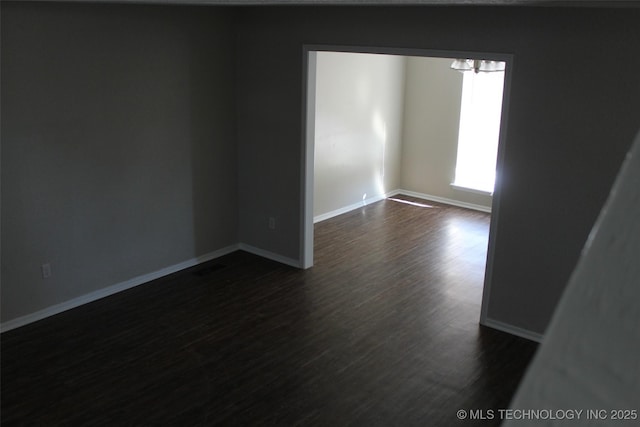 unfurnished room with dark wood-type flooring