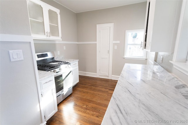 kitchen with light stone counters, white cabinetry, dark hardwood / wood-style floors, and stainless steel range with gas stovetop