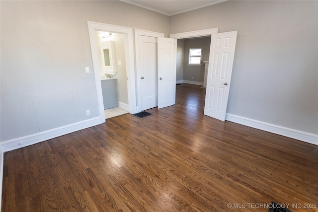 unfurnished bedroom featuring dark hardwood / wood-style flooring and connected bathroom