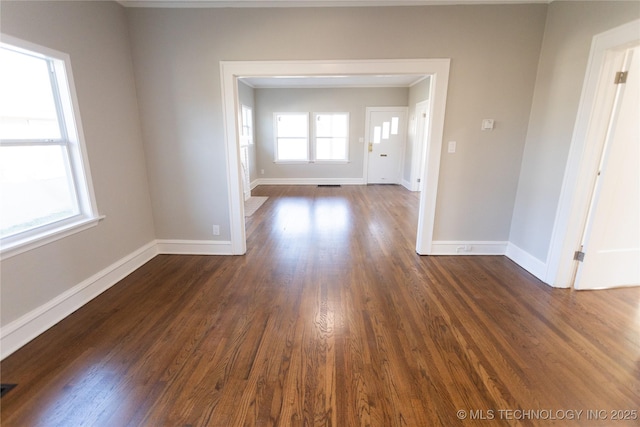 spare room with dark wood-type flooring and a healthy amount of sunlight