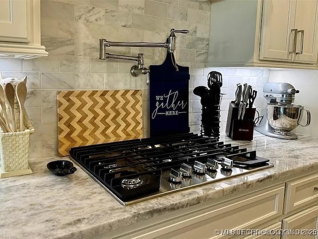 kitchen with gas stovetop, light stone countertops, and backsplash