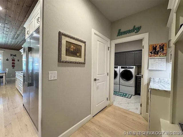 clothes washing area with washer and dryer and cabinets